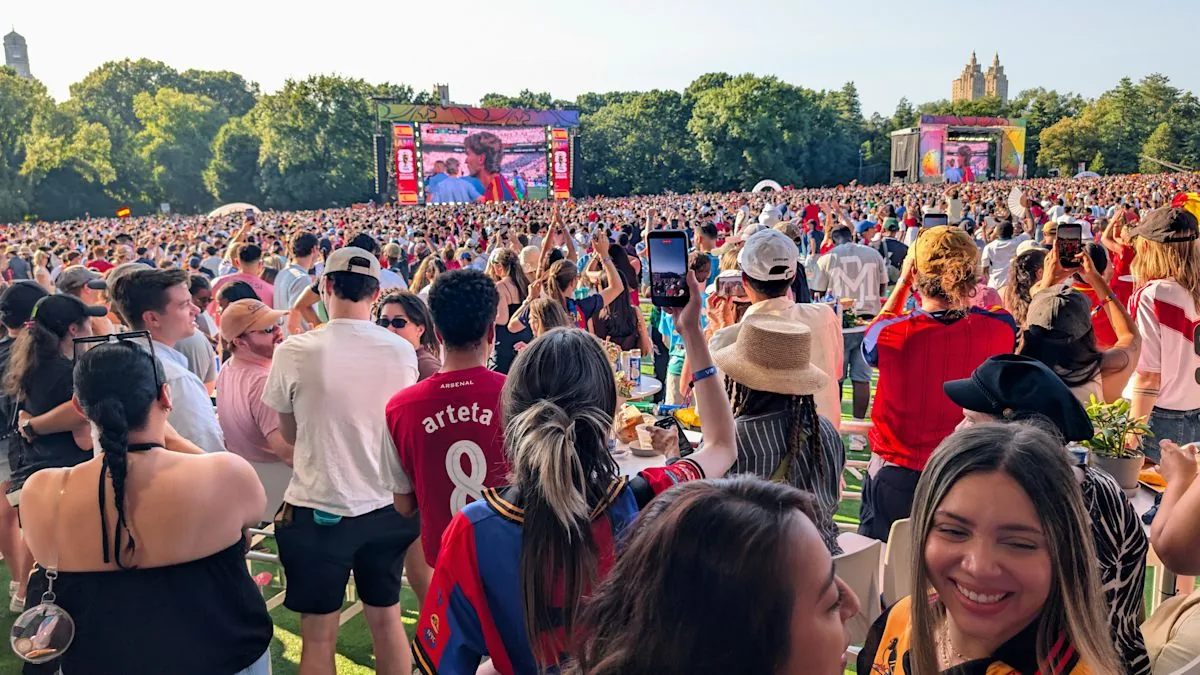 World Cup fans celebrate in a crowded street with flags and phones raised